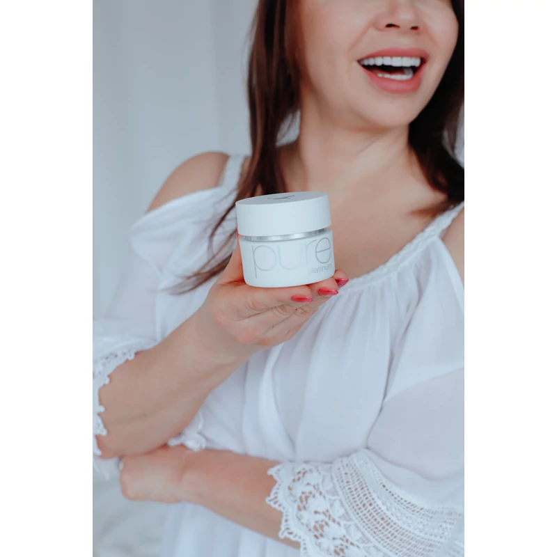 Fehér ruhájú nevető nő maga elé tartja a High Care Pure Platinum intenzív ránctalanító krémet