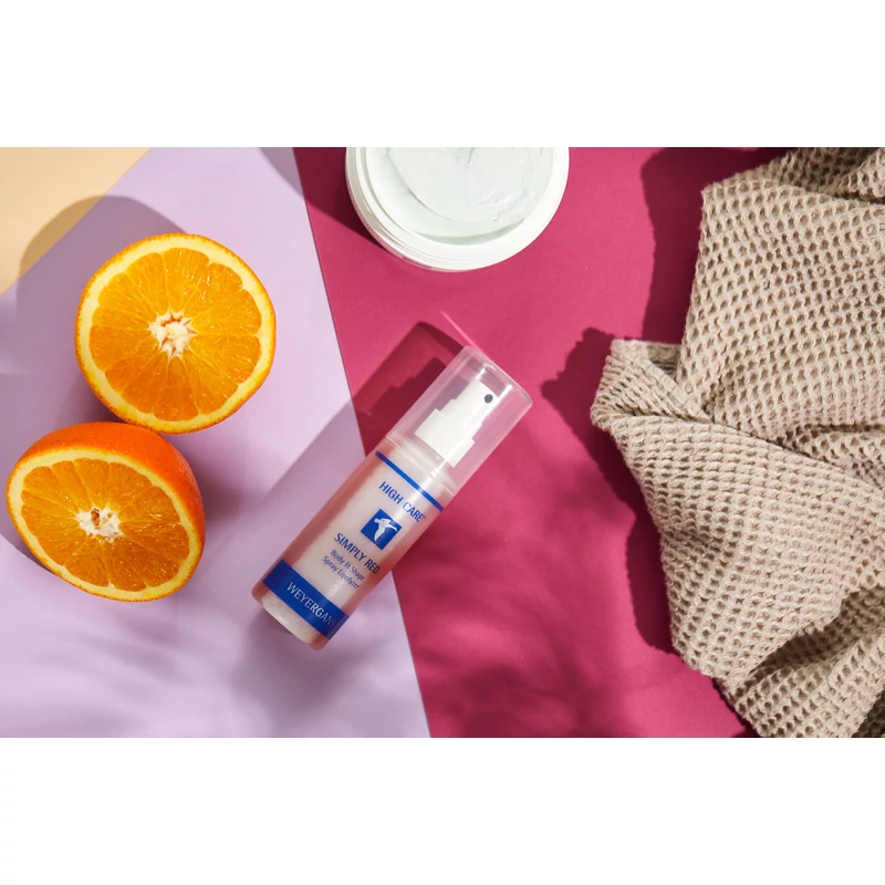 High Care Simply Red zsírbontó, alakformáló spray lefektetve egy színes felszínre, mellette egy félbevágott narancs